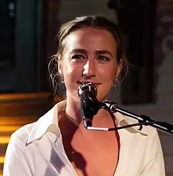 Country music singer Ingrid Andress, seated while singing into a microphone.