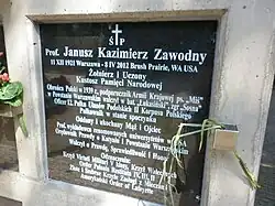 Grave marker of Janusz Kazimierz Zawodny at the Powazki Military Cemetery, Marker appears to be a vertical concrete frame inset with a slab of polished black stone (text on stone in white).