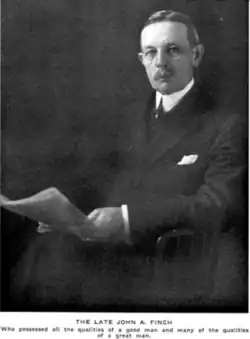 A man with glasses and a comb-over haircut looks into the camera, holding a newspaper. caption reads, "THE LATE JOHN A. FINCH, who possessed all the qualities of a good man, and many of the qualities of a great man."