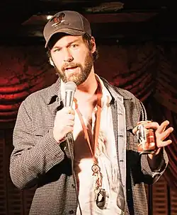 man in checked jacket and baseball hat with microphone