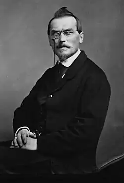 Formal photo of Barthe, fair-skinned and dark-haired, wearing mid-19th century business suit and pince-nez