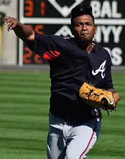 A man in a navy blue baseball jersey and gray pants