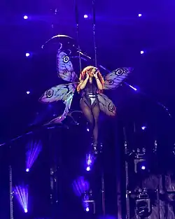 SZA being carried above the stage by wires while dressed in a butterfly costume