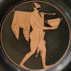 Komast with a skyphos, a staff and pipes case, tondo from a red-figure plate by Epiktetos, ca. 520s BCE–500s BCE, from Vulci, Cabinet des Médailles (n.510).