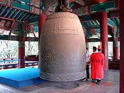 Image shows bell about three metres high, with celebrant alongside