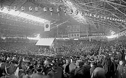 Inside of the building with a lot of spectators, the dohyō is seen in the distance