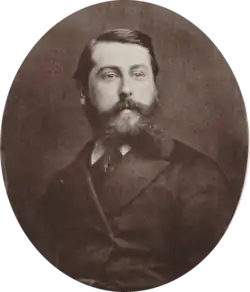 Middle aged white man with short, dark hair and a bushy beard