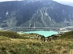 A picture of an aqua-marine lake at the foot of a mountain