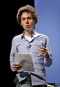 A man holds a piece of paper while he gives a speech