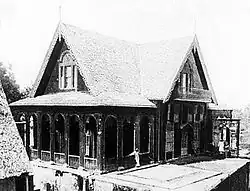 Two-storey wood house in the form of a cross, with decoratively carved ornamentation