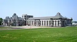 A grey stone building sits at the end of a green field.