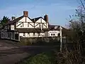 White painted building with black timbers. In the foreground is a road and road sign.