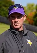 Mike Zimmer wearing a cap and sunglasses on top of his head