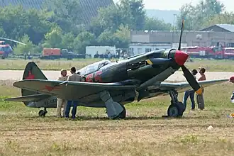 Side view of a MiG-3 painted in green and brown with the VVS insignia taking off. The slogan "Za Rodinu" (For [the] Motherland) is painted on its side.