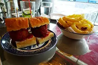 A meatball sandwich with onion rings at a London restaurant
