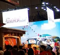 A photo of the Capcom booth at Tokyo Game Show 2010, including an Ace Attorney Investigations 2 area featuring an airplane backdrop and an inflatable figure of the "Steel Samurai" character.