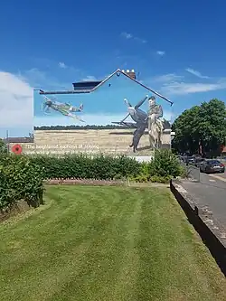 A mural on the side of a house in the town of Loughborough, UK, depicting Johnson. The house is across the road from Loughborough Grammar School, where Johnson was educated. The Mural is based upon a photograph of Johnson taken at Bazenville Landing Ground, Normandy, July 1944, with his Labrador, Sally.