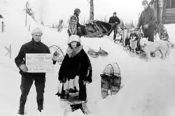 Nell Shipman and a man in the snow standing in front of a dog sled team