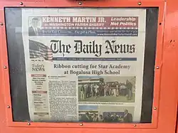 Newspaper in a bright orange vending machine with the headline "Ribbon cutting for Star Academy at Bogalusa High School"