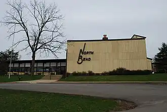 A yellow wooden lodge building with a leafless tree in front.