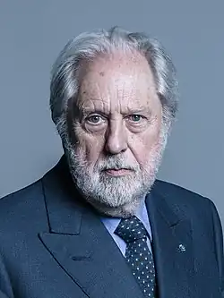 A profile image of David Puttnam. An older Caucasian male with shoulder-length white hair and a short white beard. The man is shown from his front-right profile, facing right and smiling away from the camera.