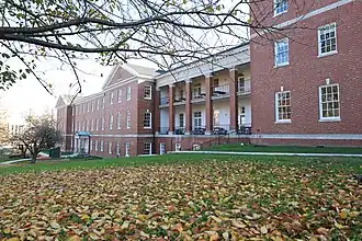 The front of Delano Hall, a three-story brick building that houses the District of Columbia International School, with grass and fall leaves in front.