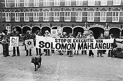 Young adult protestors hold a banner reading "Stop the execution of Solomon Mahlangu" in Afrikaans.