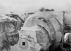Black-and-white photograph of the top part of a Greek column, with a hole drilled into the bottom.