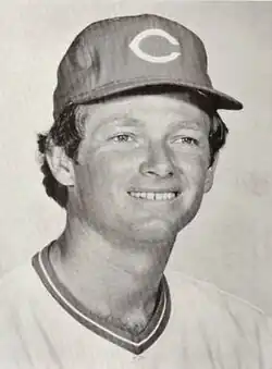 A black-and-white photograph of a man in a light baseball jersey and dark cap