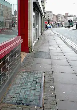 A pavement light set into the pavement outside a store (close-up)