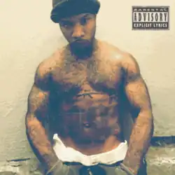 A shirtless Tory Lanez posing against a prison wall