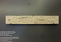 Photograph of a Roman marble sculpture, showing buildings shaking and being destroyed in an earthquake.