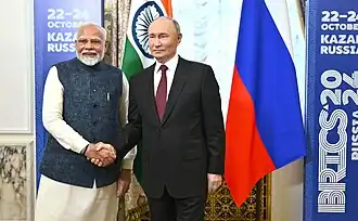 Russian President Vladimir Putin shaking hands Indian Prime Minister Narendra Modi at the 16th BRICS Summit in 2024, in front of the Indian and Russian flags.