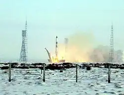 Picture of a rocket launch. The ground near the launch pad is covered in snow.