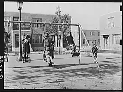 Several Black children play on a swing set at the Logan Fontenelle Housing Project in Omaha, Nebraska, 1938.