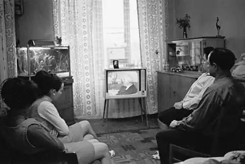 A family of textile factory workers in a common room watching TV