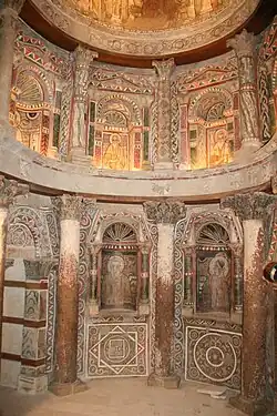 Ancient church interior with ornate stone arches, columns and religious frescoes on walls