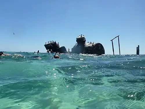 Divers explore a ship wreck adjacent to the coral reef