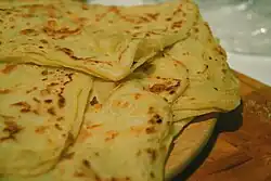 Thin layers of bread with browning on surface.