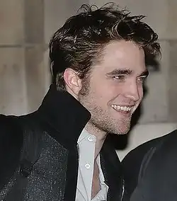 Pattinson smiling with a black coat