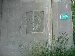 A concrete bridge support with State Highway Route 42 stamped onto it. A green sign seen to the right on the bridge support reads 0114-155 34.69