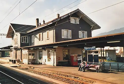 Two-story building with gabled roof next to canopy-covered platform