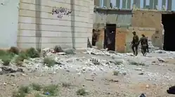 SDF fighters walk through a destroyed area in the suburbs of Raqqa, 13 June 2017