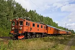 A Swedish boxcab locomotive hauling a train through the countryside