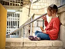 A haredi boy eats a sufganiyah in the old city of Safed.