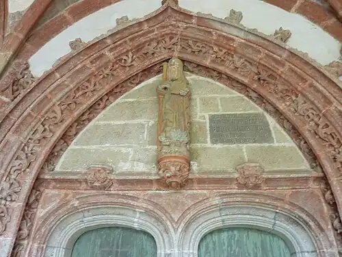 The entrance door to the church via the south porch. Over the door is a depiction of Saint Herbot with the inscription "MESSIRE IEHAN DE LAVLNAY P[RE]B[T]RE GOUVERNEUR DE CEANS FIST FAIRE CEST PORTAL COMENCE(ME)NT LE PREMIER IOVR DE IVIET LAN MIL QVATRE CE[N]TS QVATRE VINTS DIX OVIT"