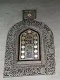 A stucco-carved window grille inside the mosque