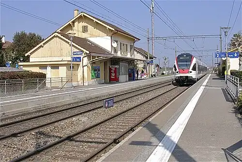 Two-story building with gabled roof and side platforms next to double-track railway line