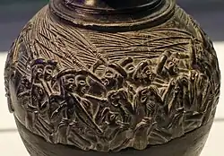 Close shot of the shoulder of the vase: one figure, in the middle of a crowd, faces left, the others face right.