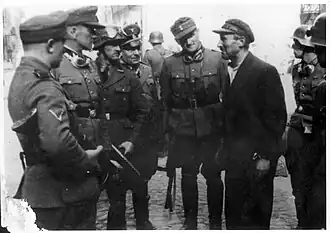 Stroop Collection Jürgen Stroop and some senior SS personnel interrogating a Jewish man during suppression of Warsaw Ghetto Uprising.The man with the goggles over his helmet (third from left) is Josef Bloshe.